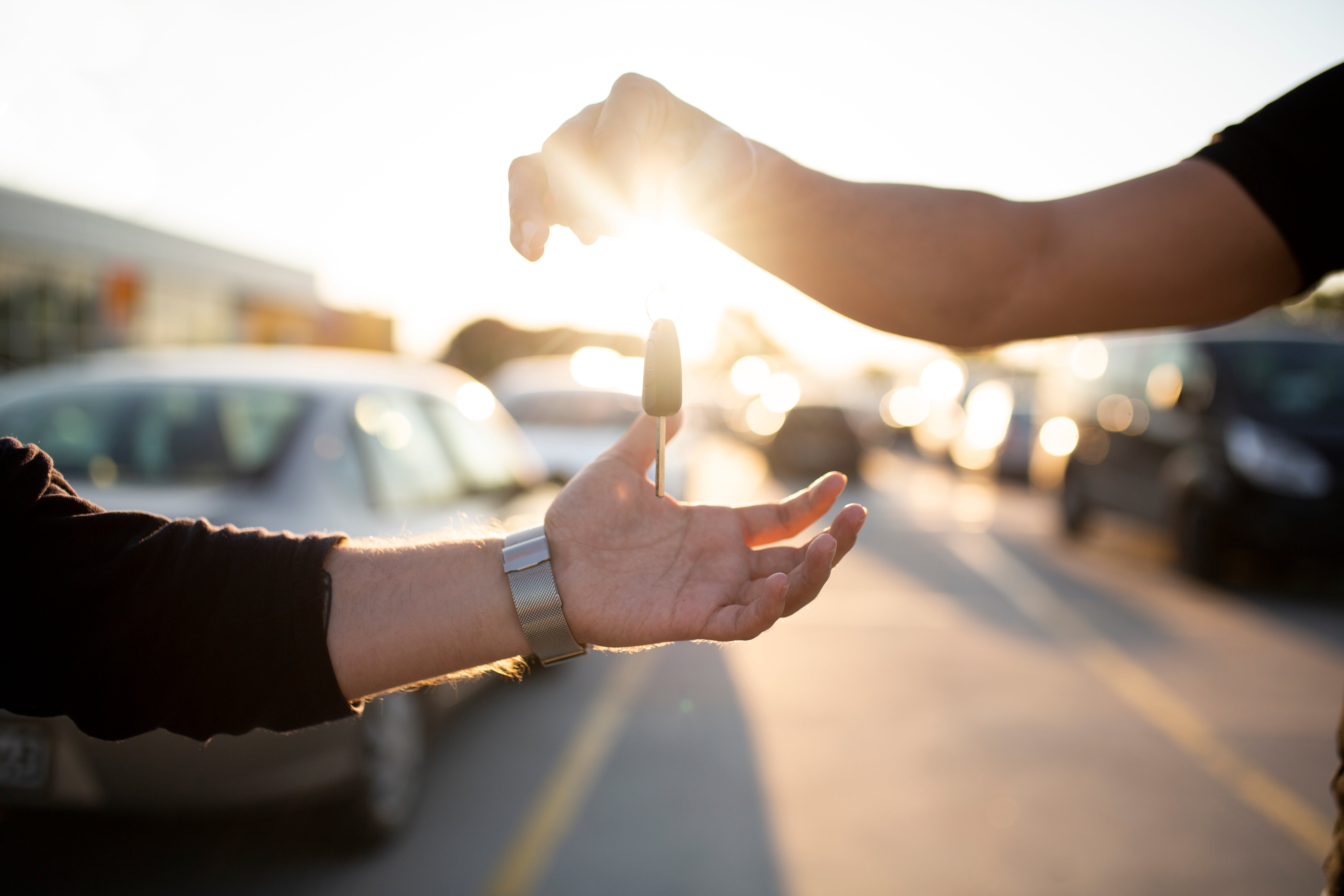 Car key handover with sunlight in the background.